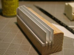 Once I had all the parts sized, cut out, and dry fit several times I got down to construction.

I started by gluing on a .125 x.125 spacer to the bottom edge of the wooden "L". Then added a .040 louver, then a spacer, another louver, etc. until I had all the louvers in place. I then glued on one end cap to stabilize the louvers and then sanded the other ends flush with the wood. I then added the other end cap and the floor of the airbox.