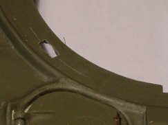 I started by marking three small rectangles on the flat surface of the hull plate below the bottom of the turret ring, and out of the way of all of the traverse mechanism. Then using a 5/64th drill bit I drilled out three holes within each drawn rectangle and then used micro files to join the holes, and square up the edges. I ended up with a rectangular through hole slightly longer and wider than the wheel collet stood on edge.